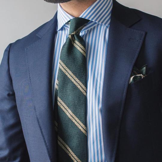Tamsiai mėlynas kostiumas, šviesiai mėlyni juostuoti marškiniai, tamsiai žalias dryžuotas kaklaraištis