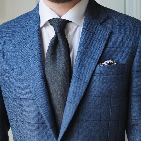 Mėlynas languotas kostiumas, balti marškiniai, tamsiai mėlynas kaklaraištis