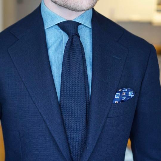 Tamsiai mėlynas kostiumas, šviesiai mėlyni marškiniai, tamsiai mėlynas kaklaraištis