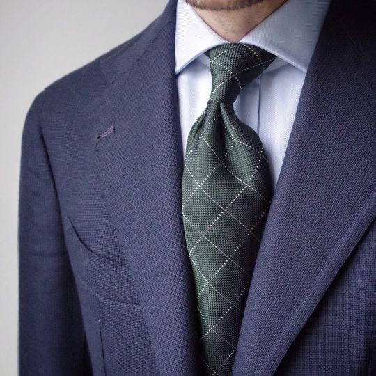Tamsiai mėlynas švarkas, šviesiai mėlyni marškiniai, tamsiai žalias languotas kaklaraištis