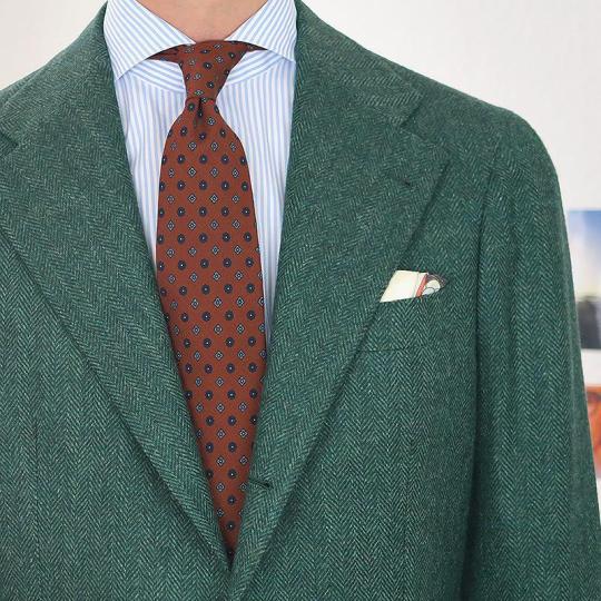 Žalias švarkas, šviesiai mėlyni dryžuoti marškiniai, oranžinis margas kaklaraištis