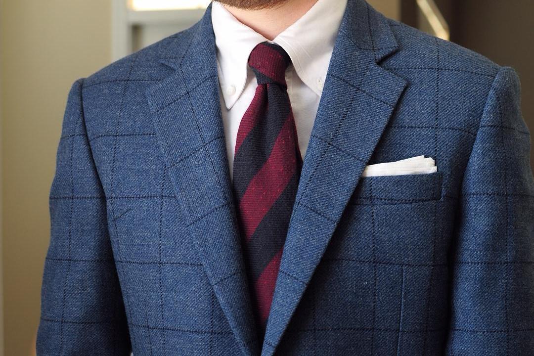 Mėlynas languotas švarkas, balti marškiniai, tamsiai raudonas dryžuotas kaklaraištis